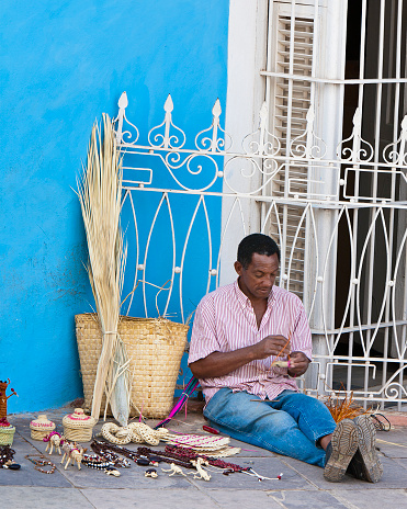 Trinidad, Sancti Spiritus Province, Cuba - January 27, 2007: A man is making straw items as souvenirs.