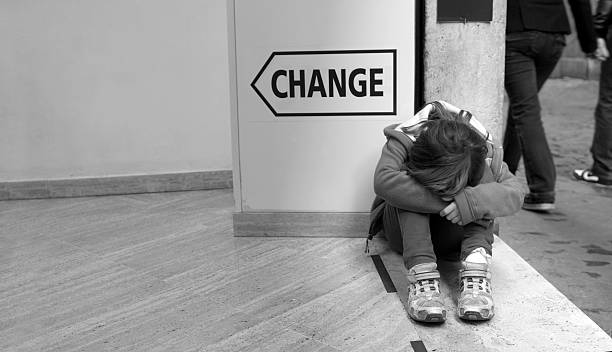 Sad girl huddled by sign saying change Horizontal image of a sad girl huddled by a sign saying "change". Related: sad girl crouching stock pictures, royalty-free photos & images