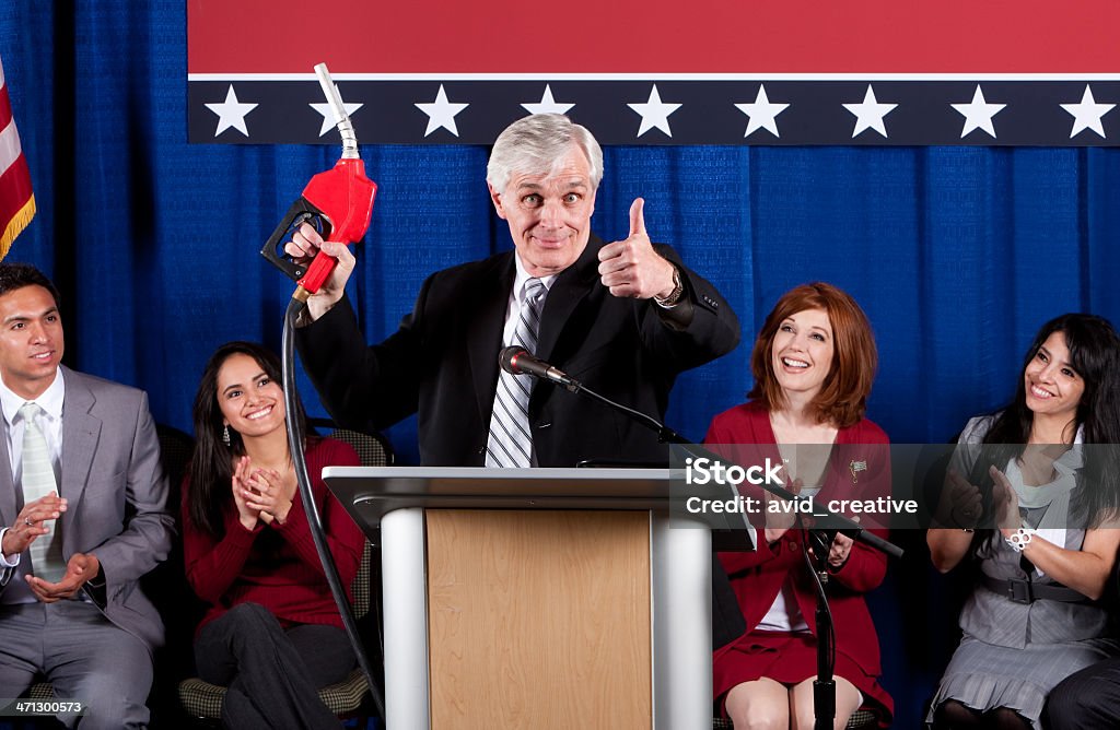 Politico al podio con ugello della pompa carburante - Foto stock royalty-free di Adulto