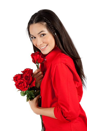 Young cute woman holding a bunch of flowers while standing against white background not isolated