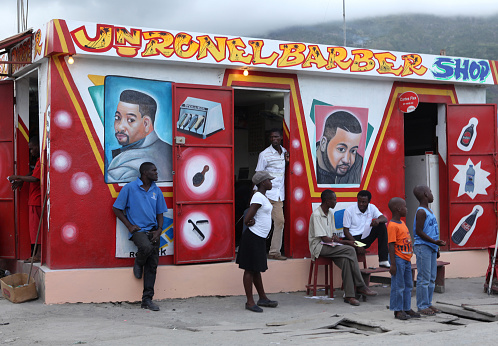 Cap-Haitien, Haiti - February 4th, 2010 : People gather outside a brightly decorated barber\\'s salon in Cap-Haitien.