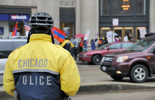 Chicago, USA - April 25, 2011: A Chicago police officer observes a group of Armenian protesters in downtown Chicago protesting the alleged genocide committed by Turks against their people in 1915.