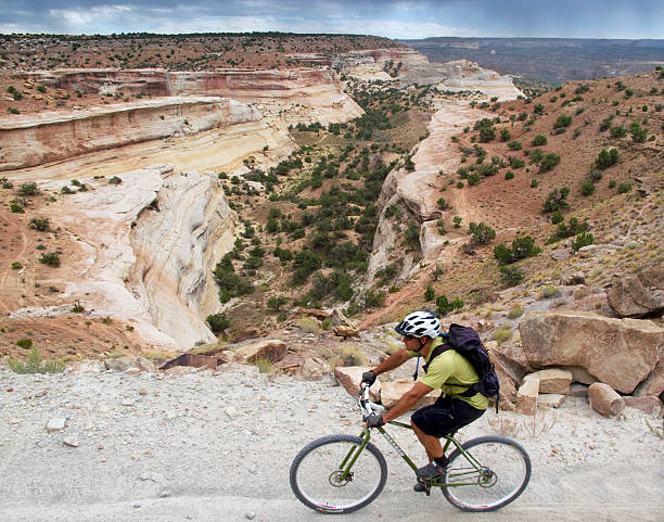 mountain biking Western rim trail, near Fruita, USA- September 20, 2010: american man mountain biking on southwest desert landscape terrain. the western rim trail outside of fruita, colorado is a mountain biking trail that closely contours a portion of the colorado river. the entire area surrounding fruita, colorado is a haven for outdoor adventure enthusiasts. throughout the united states, mountain biking has been embraced as both a way of life and a means to bring economic prosperity to rural areas. fruita colorado stock pictures, royalty-free photos & images