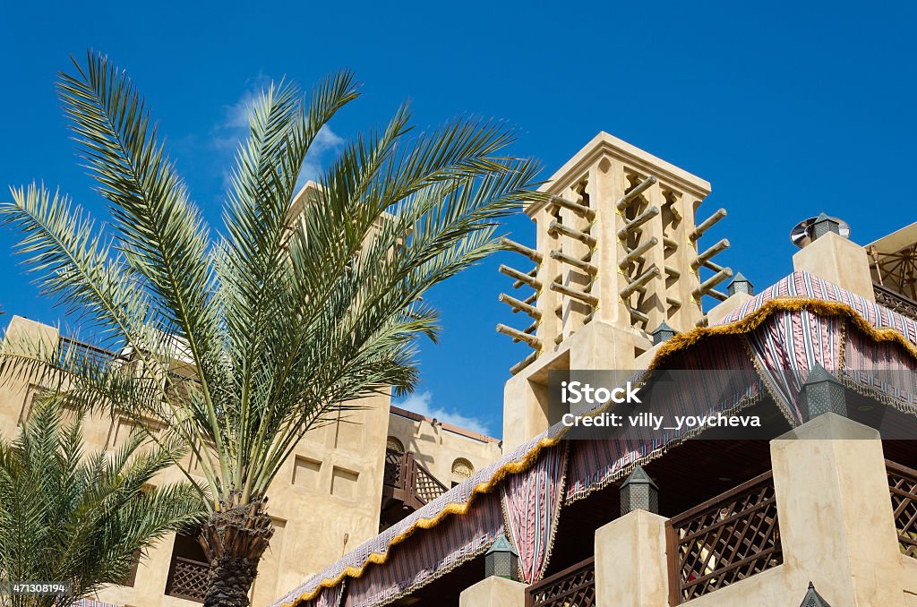 Old wind tower and palm trees, Bastakiya, Dubai, UAE. Wind tower in the Bastakiya area. Wind towers are used in the United Arab Emirates to cool their buildings. The construction of Al Bastakiya dates back to the 1890s. Dubai Stock Photo