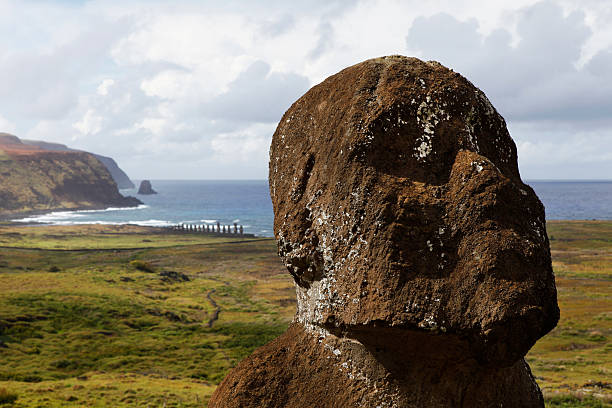 Tukuturi is an unusual moai. Its beard and kneeling posture distinguish it from standard moai. It is made of red scoria but is at Rano Raraku quarry where they mined tuff for the other moai. It is believed to be the last moai ever made. Ahu Tongariki can be seen in the background on the coast.