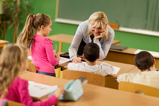 istock Happy female teacher assisting elementary students in the classroom. 471310316