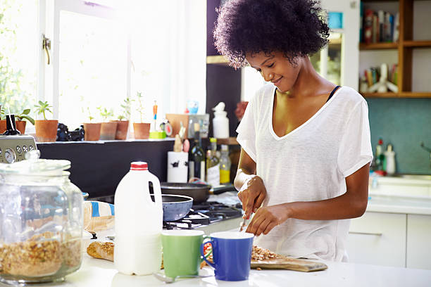 Young Woman Wearing Pajamas Preparing Breakfast In Kitchen