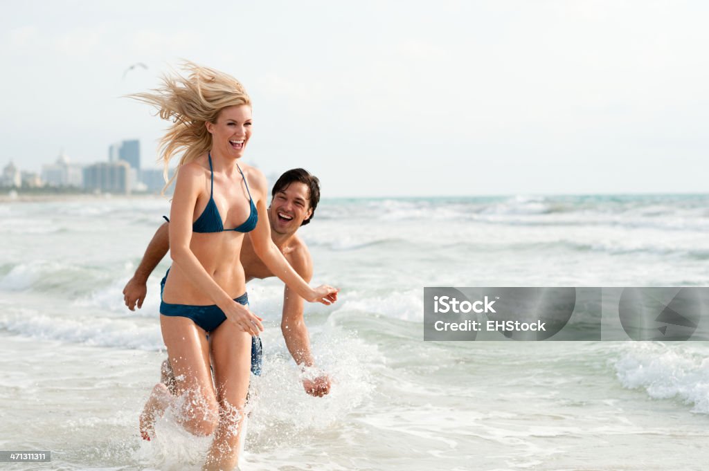 Junges Paar, Mann und Frau spielen in der Brandung am Strand - Lizenzfrei Paar - Partnerschaft Stock-Foto