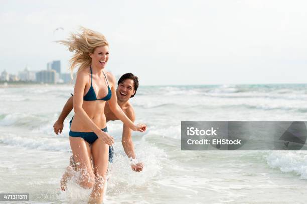 Giovane Coppia Uomo E Donna Giocando Nel Surf Al Beach - Fotografie stock e altre immagini di Relazione di coppia