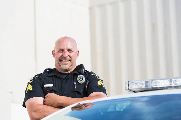 istock Happy police officer standing next to cruiser 471313496