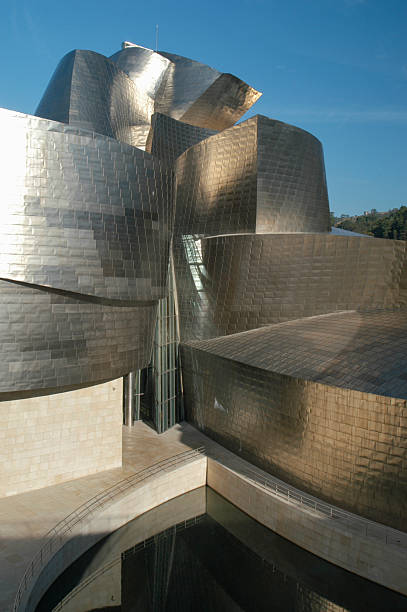 Bilbao, Spain - September 17, 2004: Bright Spanish sun shines on the metal curves of the Guggenheim Museum Bilbao. Made from limestone, glass, and titanium, the building was designed by architect Frank Gehry and is widely cited as one of the most successful buildings of its time. 
