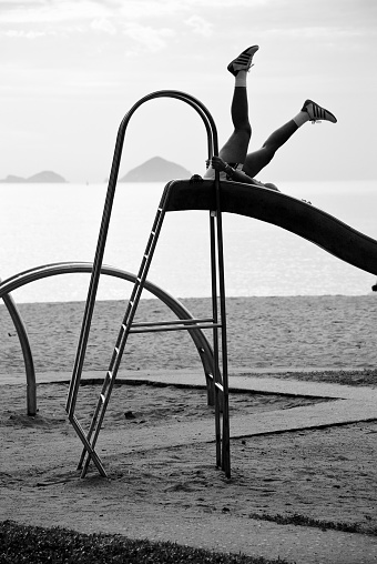 Nha Trang, Vietnam - July 8, 2007: A Vietnamese woman engages in early morning exercise on a playground on the beach. Many Vietnamese start the day with exercise in public places.