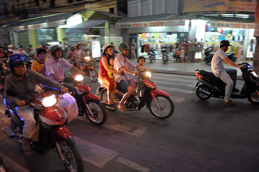 Ho Chi Minh City, Vietnam - February 14, 2023: Motorcycles and cars pass by the main entrance and clock tower of Ben Thanh Market.