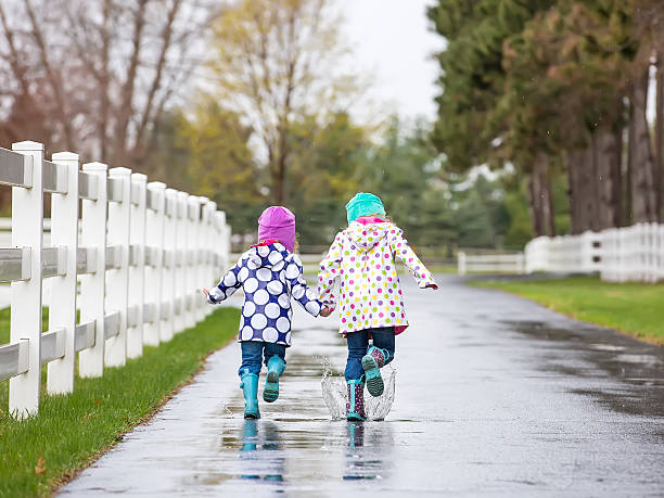 istock Two Young Girls Running Through Puddles in Rain 471315050