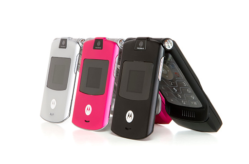 Nashville, USA - November, 19th 2005: A row of three pink, silver, and black colored Motorola Razor cell phones in a line half folded open against a white background in Nashville TN.