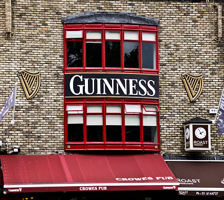 Dublin, Republic of Ireland - 15th July, 2011: Sign and emblem of Guinness above Crowes Pub in the Ballsbridge area of Dublin. A canopy and clock for the Roast restaurant is in the lower right of the photo.