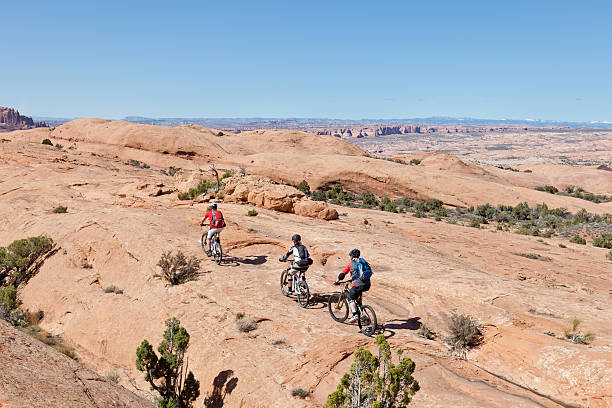 Slickrock Trail, Moab Three mountainbiker on their way along the famous Slickrock Trail nearby the village of Moab, Utah. The so-called "slickrock" sandstone, which forms the majority of the trail's surface, is not slick at all, but has a surface much like sandpaper. The rubber tires of a mountain bike will grip readily to its surface on all but the steepest hills. slickrock trail stock pictures, royalty-free photos & images