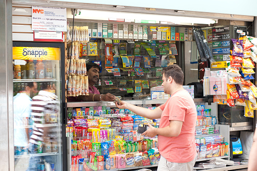 Manhattan, New York, USA - August 12, 2011: Customer pays for an item to a news stand vendor in Herald Square. Popular items in most news stands in New York City are lottery tickets, candies, cigarettes and refreshments.