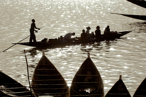 Mopti, Mali - March, 13th 2006: A ferry boat with passengers in silhouette at dusk crosses the River Niger at Mopti