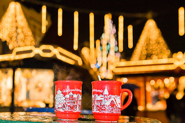 Linz, Austria - December 19, 2008: two screen-printed red cups of hot punch with smoke coming out. On the background are the lights of the Christmas market in the Hauptplatz of Linz, the baroque main square of the city.