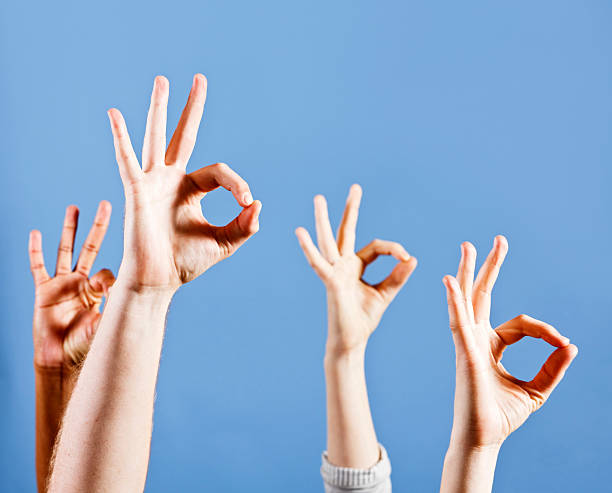 Four mixed hands signalling OK with gestures against sky blue
