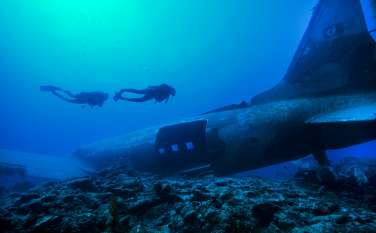 Divers enjoying the sunny clear waters of Mediterranean Sea on the artificial plane wreck in Karaada