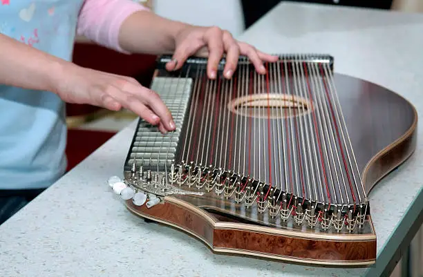 Playing on zither musical instrument.
