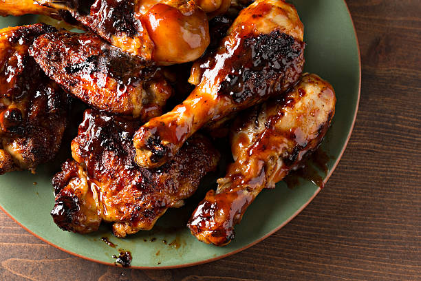Close Up Barbecued Chicken A high angle extreme close up horizontal photograph of some barbecued chicken drumsticks and thighs on a green platter. chicken bbq stock pictures, royalty-free photos & images