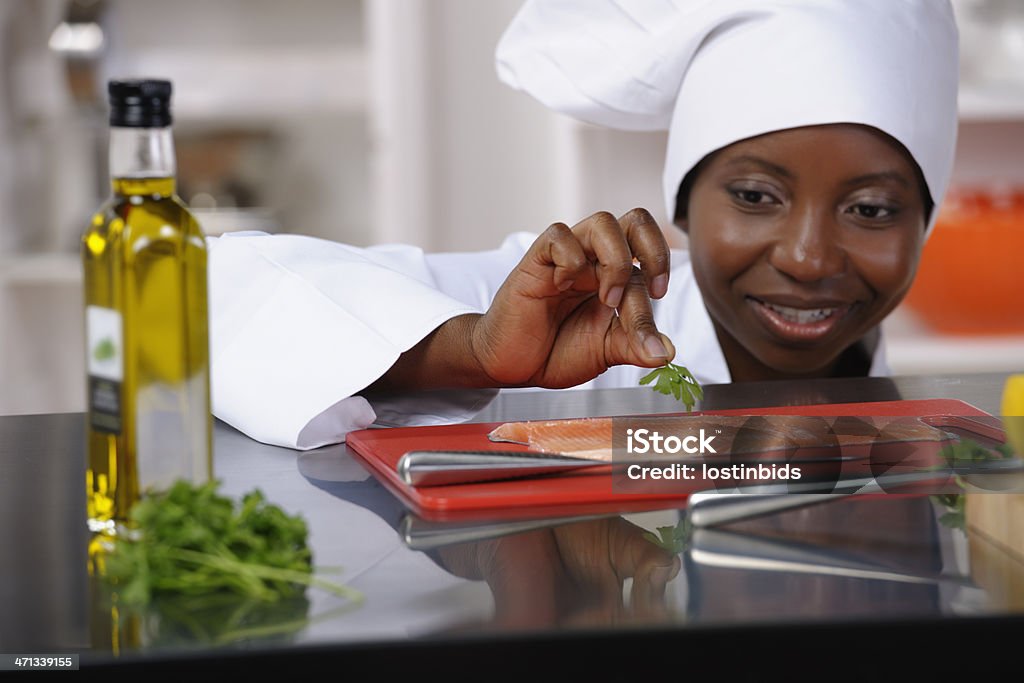 Close-up de uma mulher afro-americana Chef preparação de peixes - Foto de stock de Chef de cozinha royalty-free