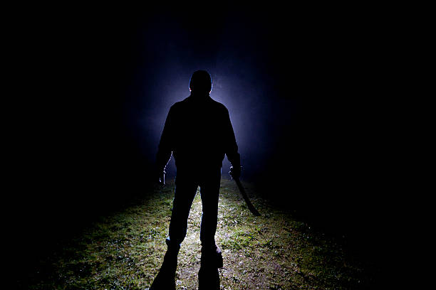 Psycho Killer - Machete Dark, foggy outdoor silhoette of a man wearing a leather jacket, knit cap and gloves holding a machette. Machete stock pictures, royalty-free photos & images