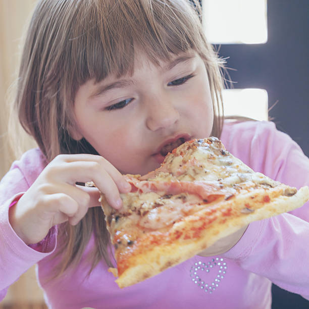 istock little girl eating pizza 471345648