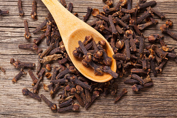 Cloves closeup Closeup of cloves in wooden teaspoon on wooden background; Adobe RGB color space;  clove spice stock pictures, royalty-free photos & images