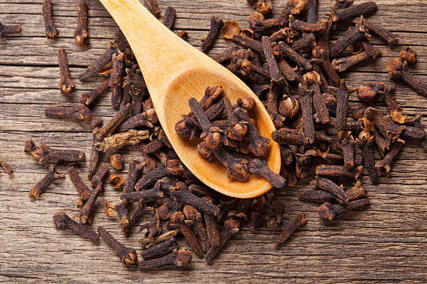 Cloves closeup Closeup of cloves in wooden teaspoon on wooden background; Adobe RGB color space;  organic spice stock pictures, royalty-free photos & images