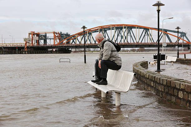 Active senior keeping his feet dry Active senior keeping his feet dry in the flooded street at the river bank of the city "Zutphen" in the Netherlands. Focus on senior. ijssel photos stock pictures, royalty-free photos & images