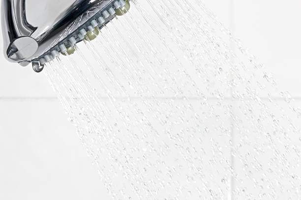 Close up of water from a shower head against white tiles in a shower, captured using fast strobes. One of a series of images.