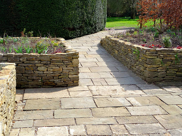 Image of raised garden beds with flagstone paving patio, wheelchair-friendly Photo showing a sunken garden with raised beds made from dry-stone walls and a patio of flagstone paving.  The garden is designed to be accessible for gardeners in wheelchairs, with the sloped pathway leading to the flowerbeds. hardscape photos stock pictures, royalty-free photos & images