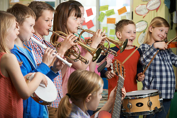 grupo de estudiantes jugando en la escuela de orquesta juntos - plucking an instrument fotografías e imágenes de stock