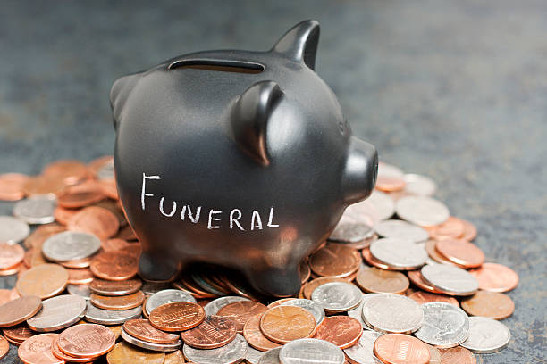 "Funeral" Piggy Bank on Coins A coin piggy-bank with "Funeral" written on it sitting on a pile of coin. Funeral stock pictures, royalty-free photos & images