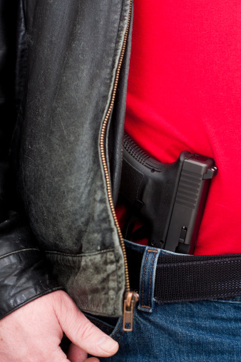 A modern, polymer (Glock), .45 caliber semiautomatic pistoltucked into his waistband (mexican carry) under a leather jacket. 