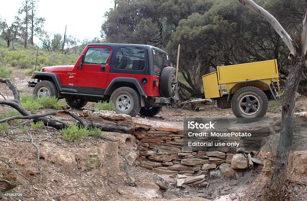 Red Jeep pulling yellow offroad trailer through Flinders Ranges Flinders Ranges, Australia - October 7, 2005: Red 1997 TJ Jeep Wrangler pulling yellow offroad trailer through the Northern Flinders Ranges. Travelling a lesser used Public Access Road South from Warraweena over a hand made stone bridge. Vehicle Trailer Stock Photo