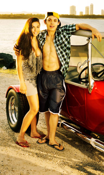 istock Young couple at dusk next to a red hot rod 471354329