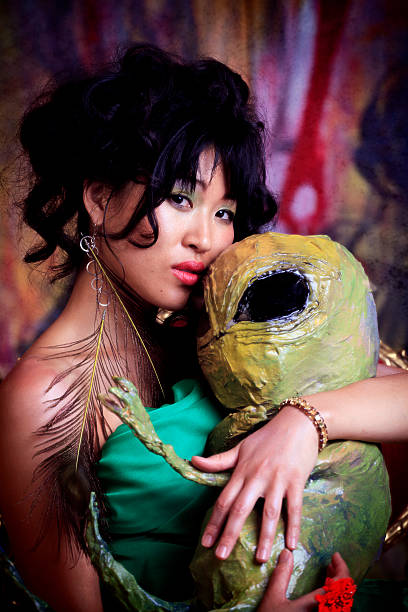Beautiful woman wearing a green dress and holding a green alien baby.