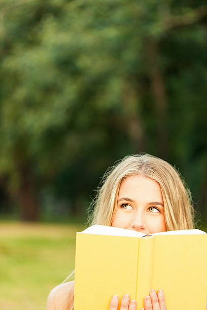 istock Distracted Young Woman With Book In Garden 471356889