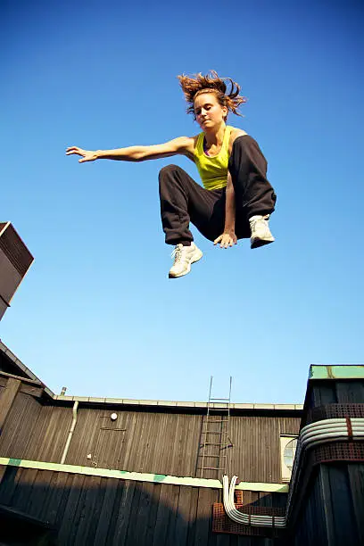 A young traceur in freefall while demonstrating the ability to react to challenges within the immediate environment in parkour