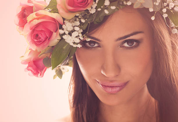 Spring Fairy Dreamy portrait of a beautiful brunette Caucasian woman with leaves and flowers in her hair. Cross processed with warm colors. beauty and beast rose stock pictures, royalty-free photos & images