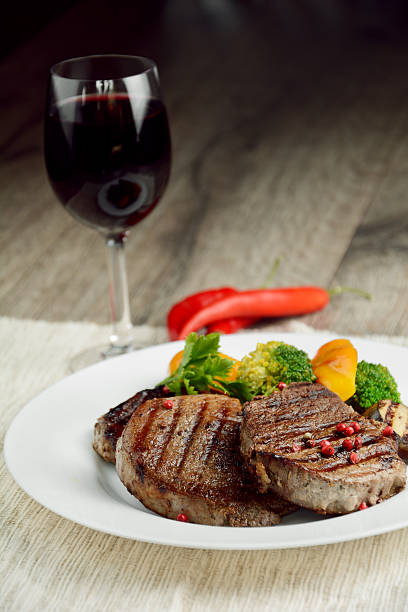 istock Pepper beef steaks on a white plate with a glass of red wine 471360188