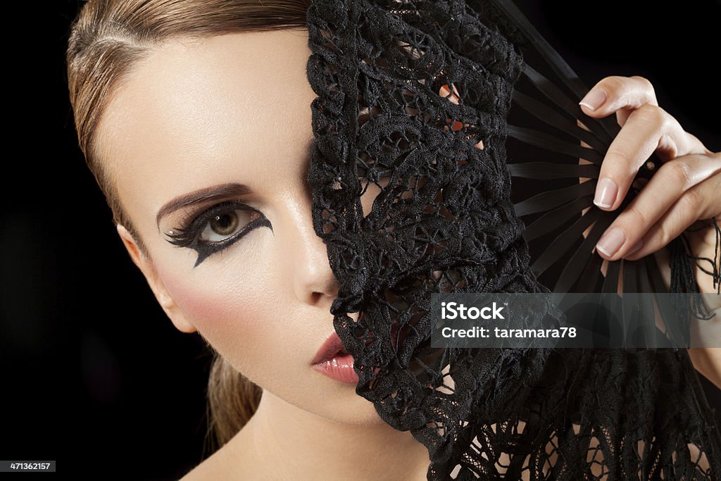 Woman behind the fan Close up portrait of a beautiful brunette woman with fashion make-up hiding behind the black fan. False Eyelash Stock Photo