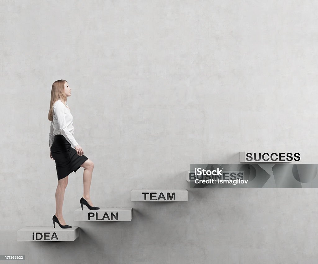 A young businesswoman climbing up stairs Young business woman is going up to the stairs. A concept of successful business project Businesswoman Stock Photo