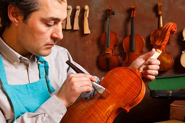 Violin maker painting violin,