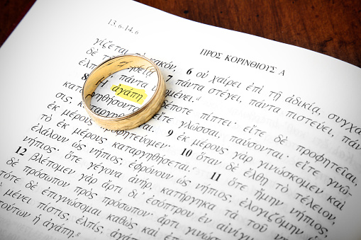 A wedding ring sits on the New Testament scriptures, in the original Greek, encircling the highlighted word 